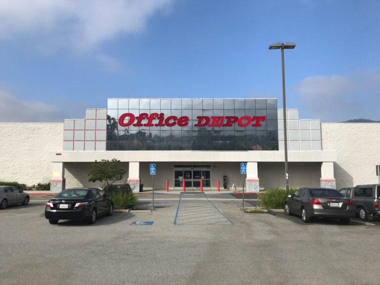 A large office depot store with cars parked in front of it.