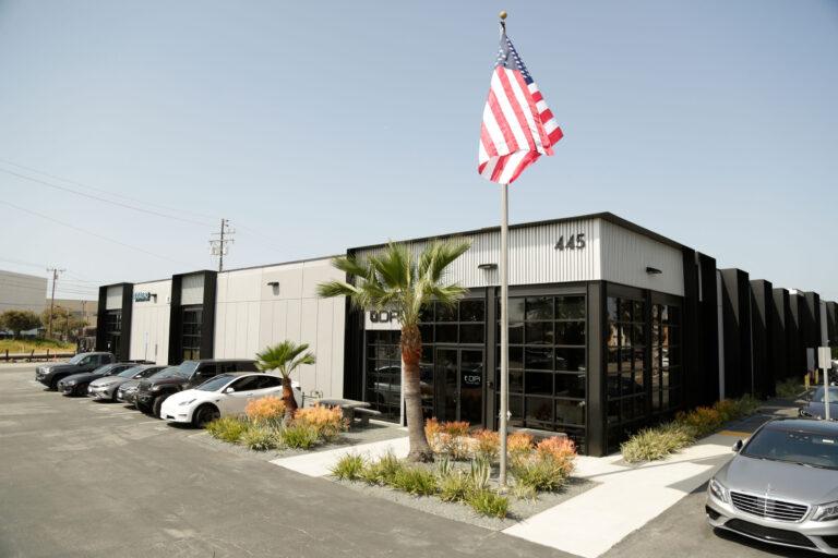 A car dealership with an american flag on the pole.