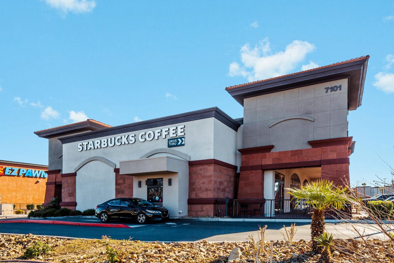 A starbucks coffee shop with cars parked in front of it.