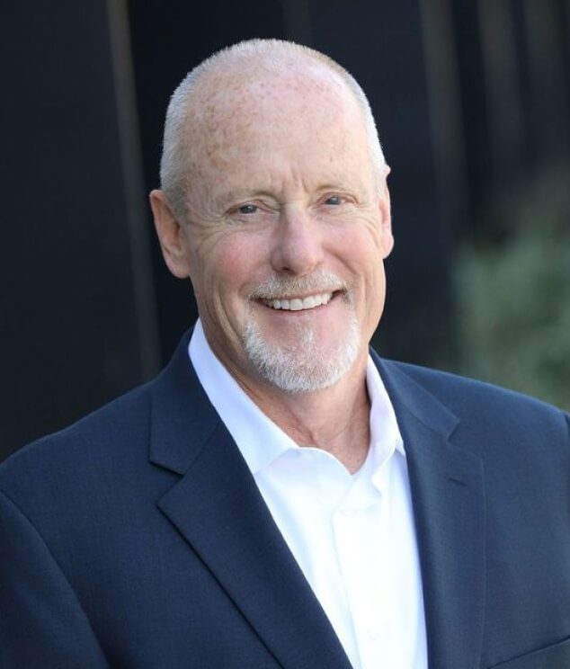 A man in a suit and tie smiling for the camera.