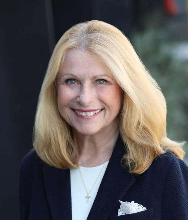 A woman with blonde hair and wearing a jacket.