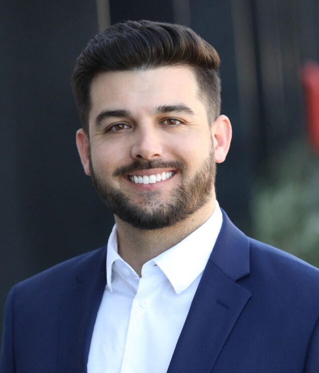 A man in a suit and tie smiling for the camera.