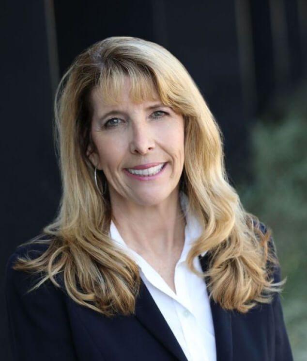 A woman with long blonde hair wearing a white shirt and jacket.