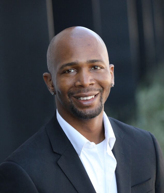 A man in a suit and tie smiling for the camera.