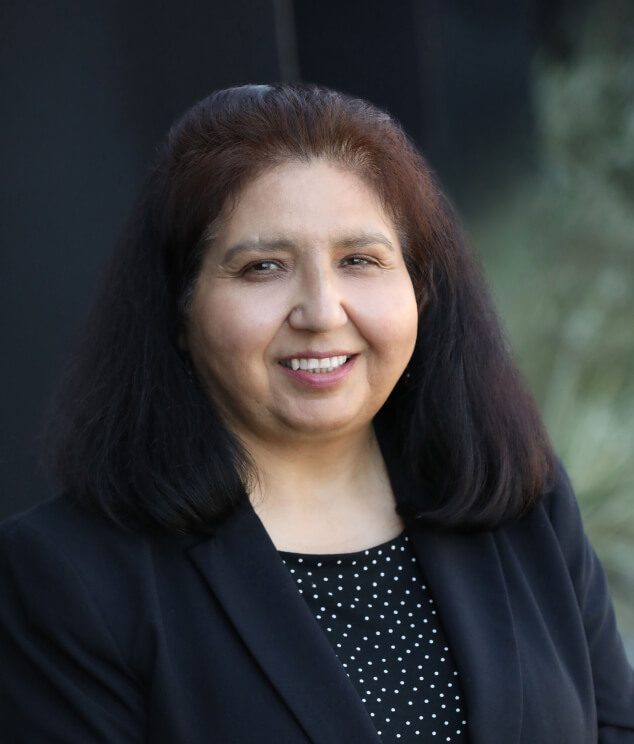 A woman with long hair and black jacket smiling.