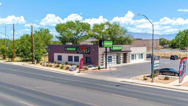 A street view of a motel with cars parked on the side.